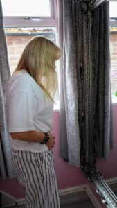 Neurodivergent person looking out to sea during summer, reflecting on body image and sensory overwhelm.
