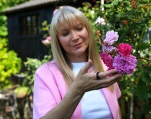 Becky Stone looking thoughtfully at flowers in a garden