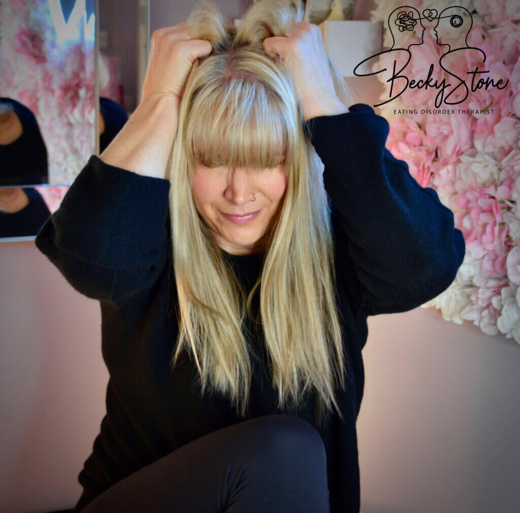 Becky Stone holding her hands beside her head to illustrate the critical eating disorder voice